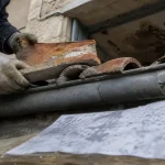 Rénovation toiture Marseille : couvreur remplace des tuiles canal près d’une gouttière fissurée